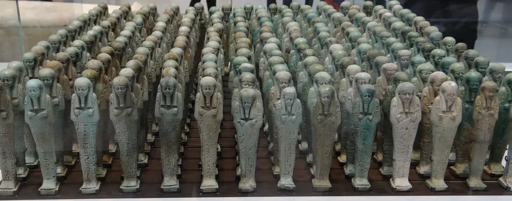 Reihe von Uschebti-Figuren aus Fayence in einer Museumsvitrine